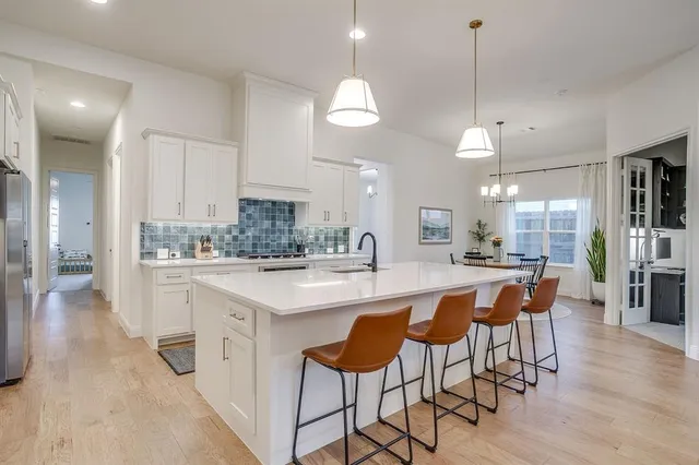 a large kitchen with kitchen island a island a sink a stove a dining table and chairs