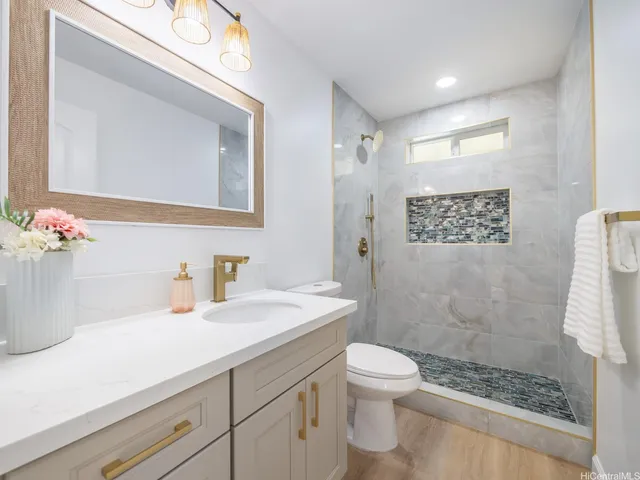 a bathroom with a granite countertop sink a toilet a mirror and shower
