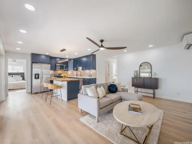 a living room with furniture kitchen view and a wooden floor
