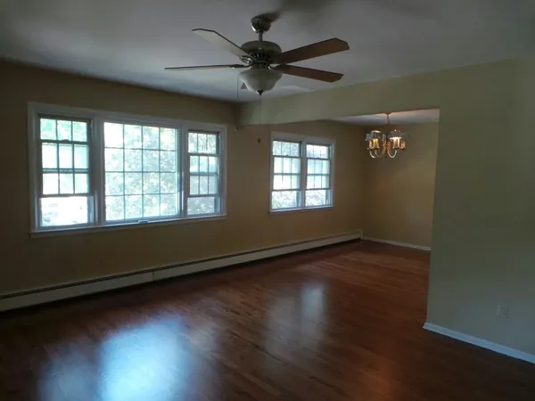 a view of an empty room with wooden floor and a window