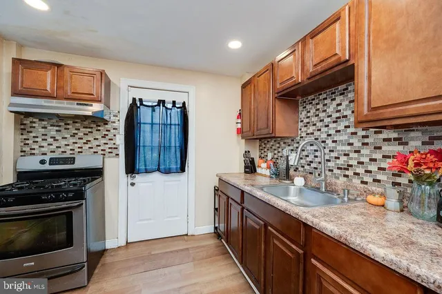 a kitchen with granite countertop a stove a sink dishwasher and a microwave oven with wooden cabinets