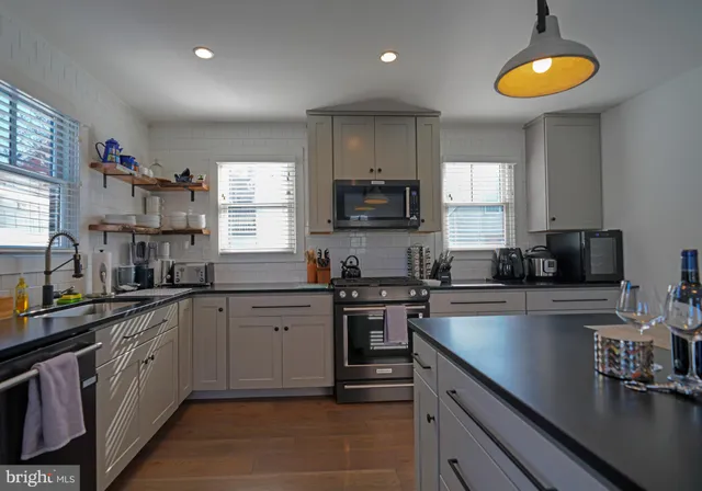 a kitchen with stainless steel appliances granite countertop a sink a stove cabinets counter space and a window