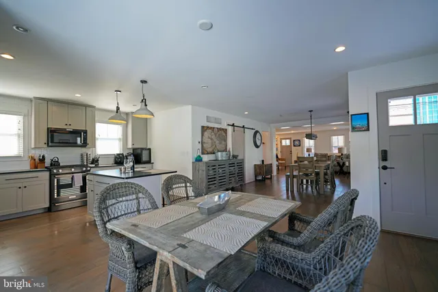 a dinning area with granite countertop lots of wooden furniture a refrigerator and chandelier