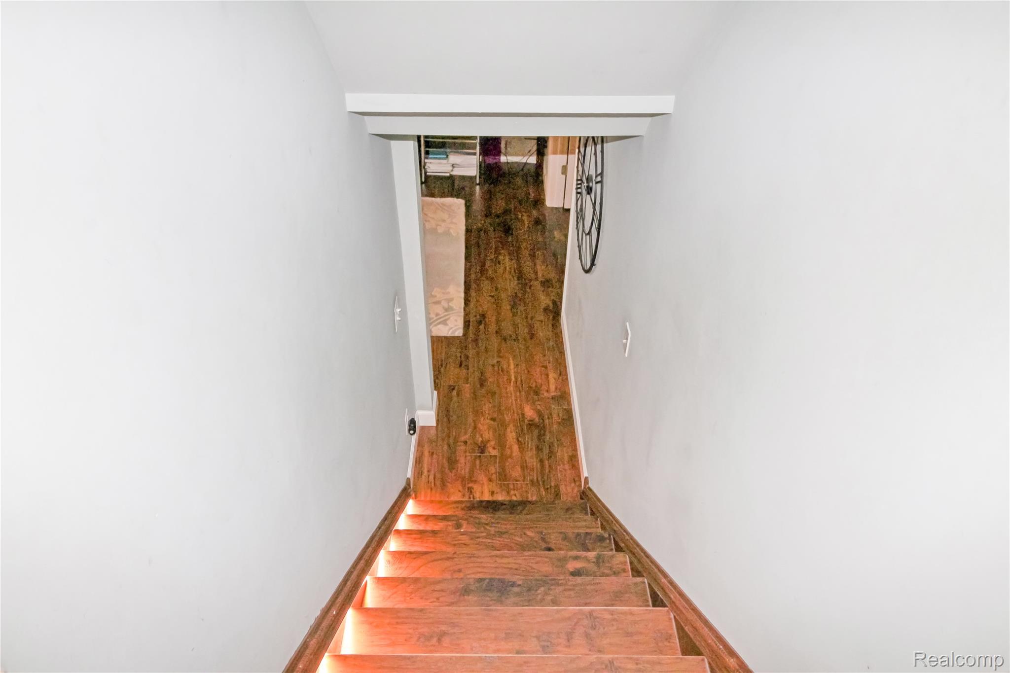 5953 Cooper Street Taylor, MI 48180 - Photo 17 of 33 Hardwood staircase with integrated step lighting, white painted walls, wood-finish flooring at the base, and a white doorway trim