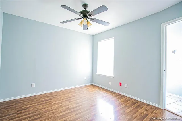 an empty room with a window and a ceiling fan