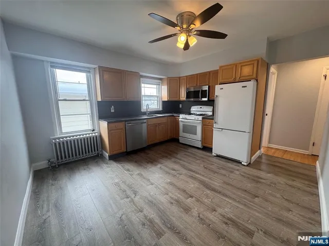a room with furniture a ceiling fan wooden floor and window