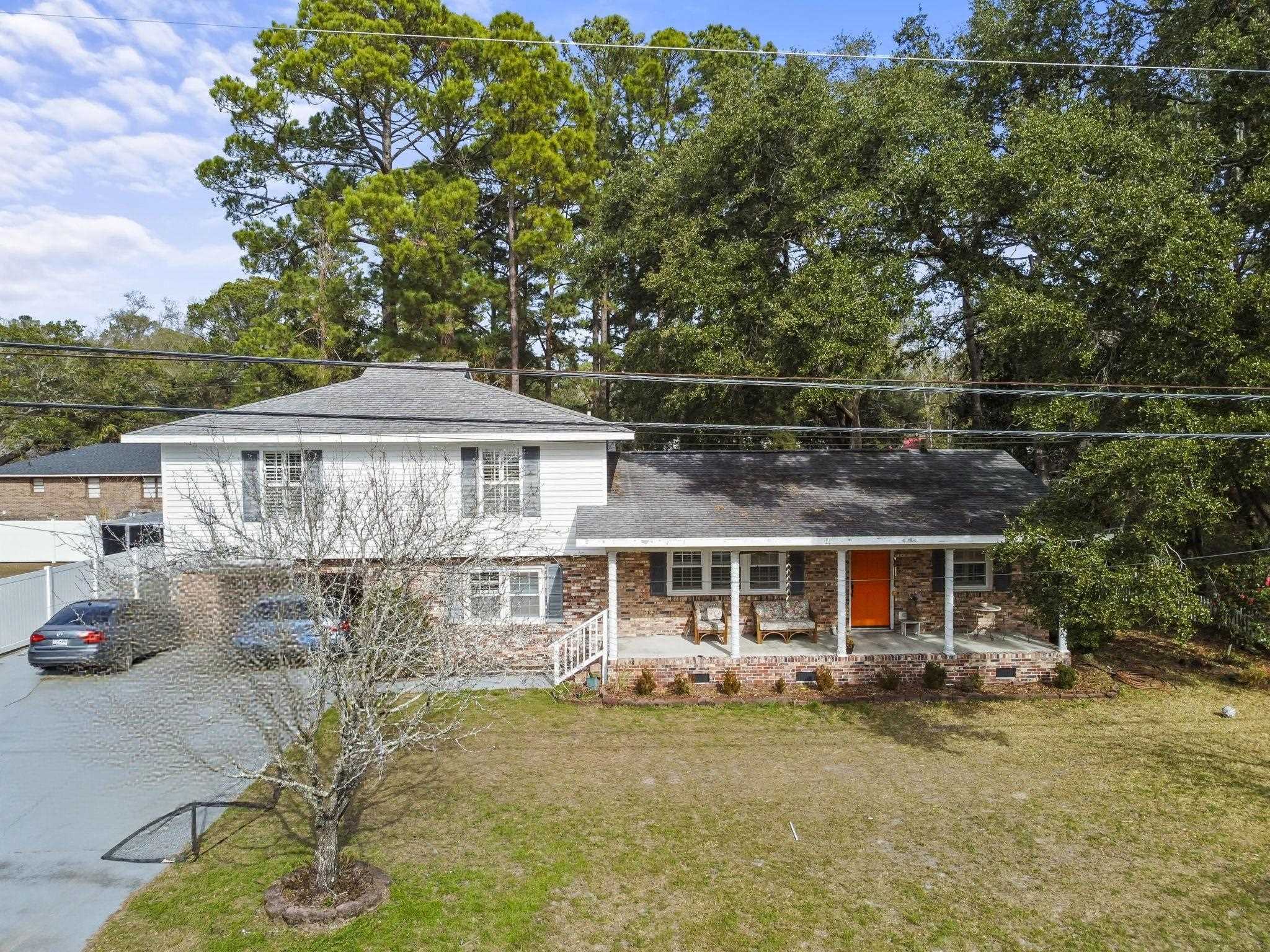 View of front of property featuring a porch, a front lawn, concrete driveway, and roof with shingles