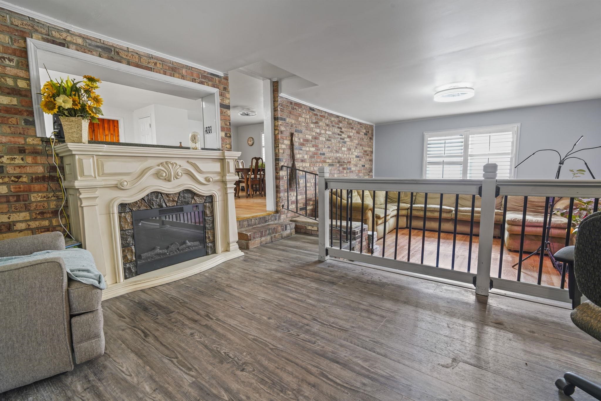 408 Rosemary Street Georgetown, SC 29440 - Photo 12 of 34 Living area featuring brick wall, wood finished floors, and a glass covered fireplace