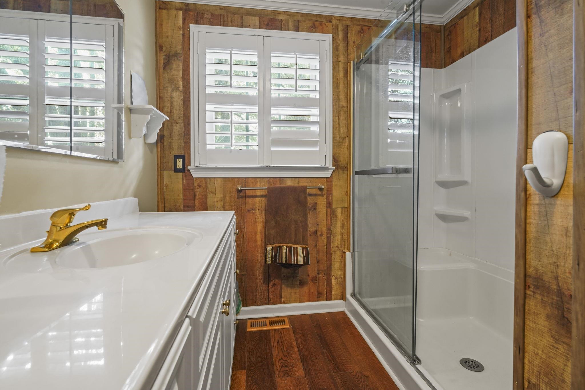 408 Rosemary Street Georgetown, SC 29440 - Photo 22 of 34 Bathroom featuring vanity, a stall shower, dark wood-style floors, and wood walls