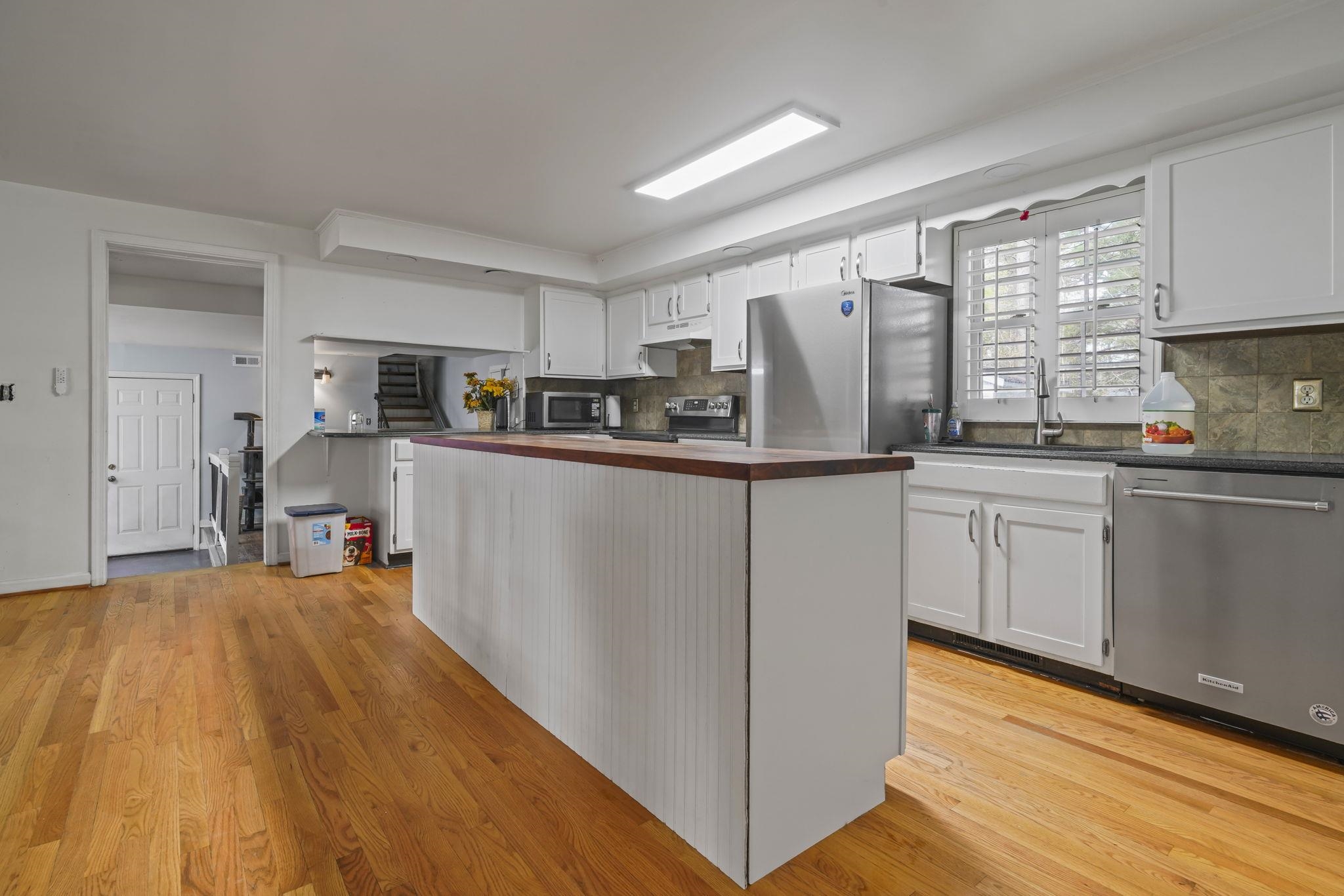 408 Rosemary Street Georgetown, SC 29440 - Photo 5 of 34 Kitchen featuring white cabinets, stainless steel appliances, light wood-type flooring, backsplash, and crown molding