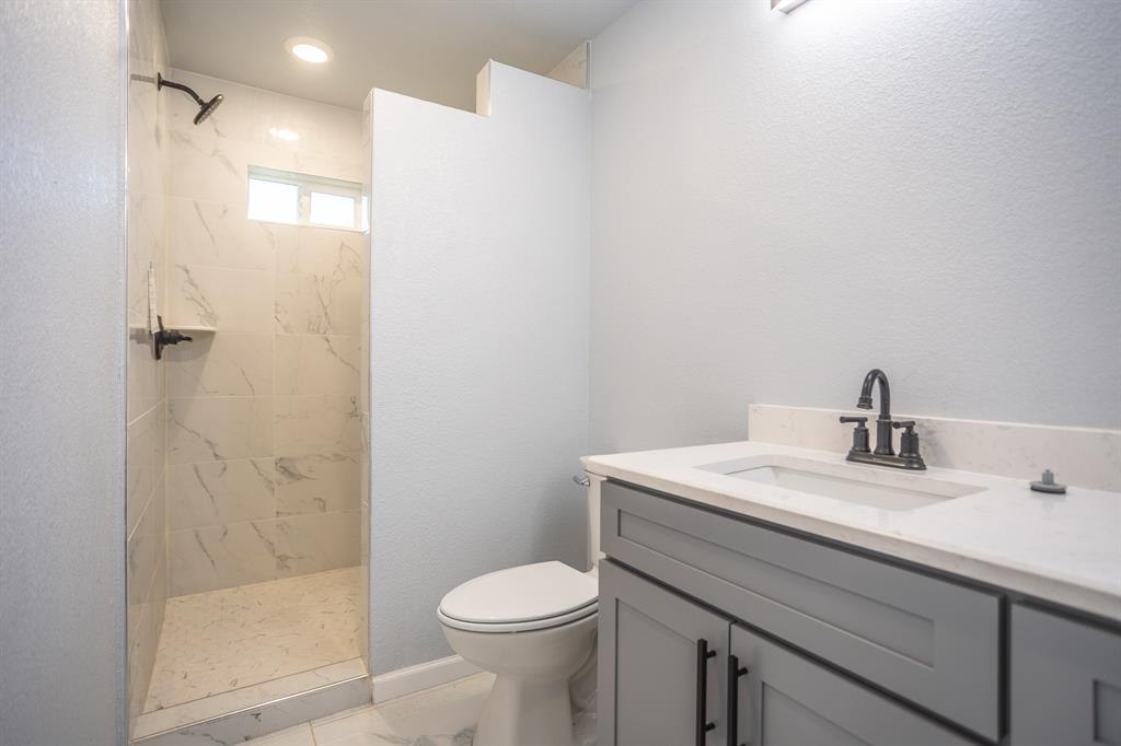 815 Ritchey Street Gainesville, TX 76240 - Photo 9 of 18 a bathroom with a sink a toilet and shower