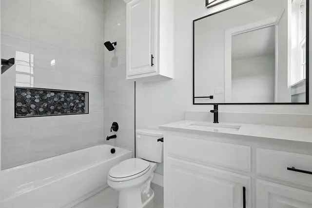 a bathroom with a bathtub sink vanity and toilet