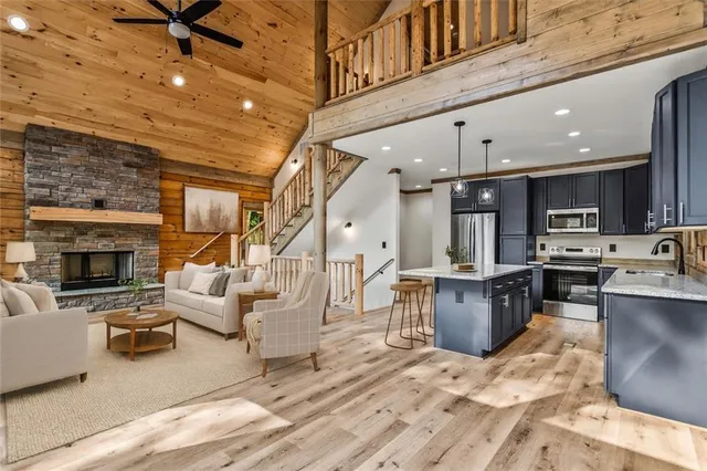 a kitchen with stainless steel appliances kitchen island granite countertop a refrigerator a stove a sink dishwasher a dining table and chairs with wooden floor