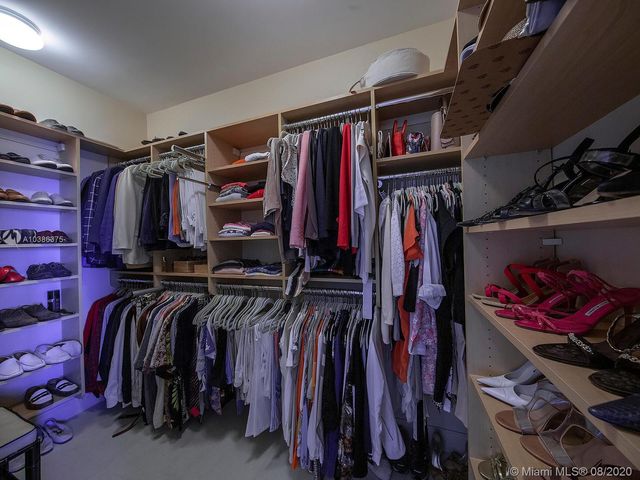 a view of walk in closet with clothes and shoes