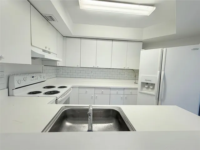 a kitchen with a refrigerator sink and white cabinets