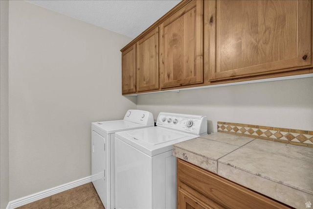 3155 South Hidden Dr Street, Unit 248 St. George, UT 84790 - Photo 15 of 24 Laundry area featuring wood-finish cabinetry, tile countertop, decorative tile backsplash, and light-toned flooring
