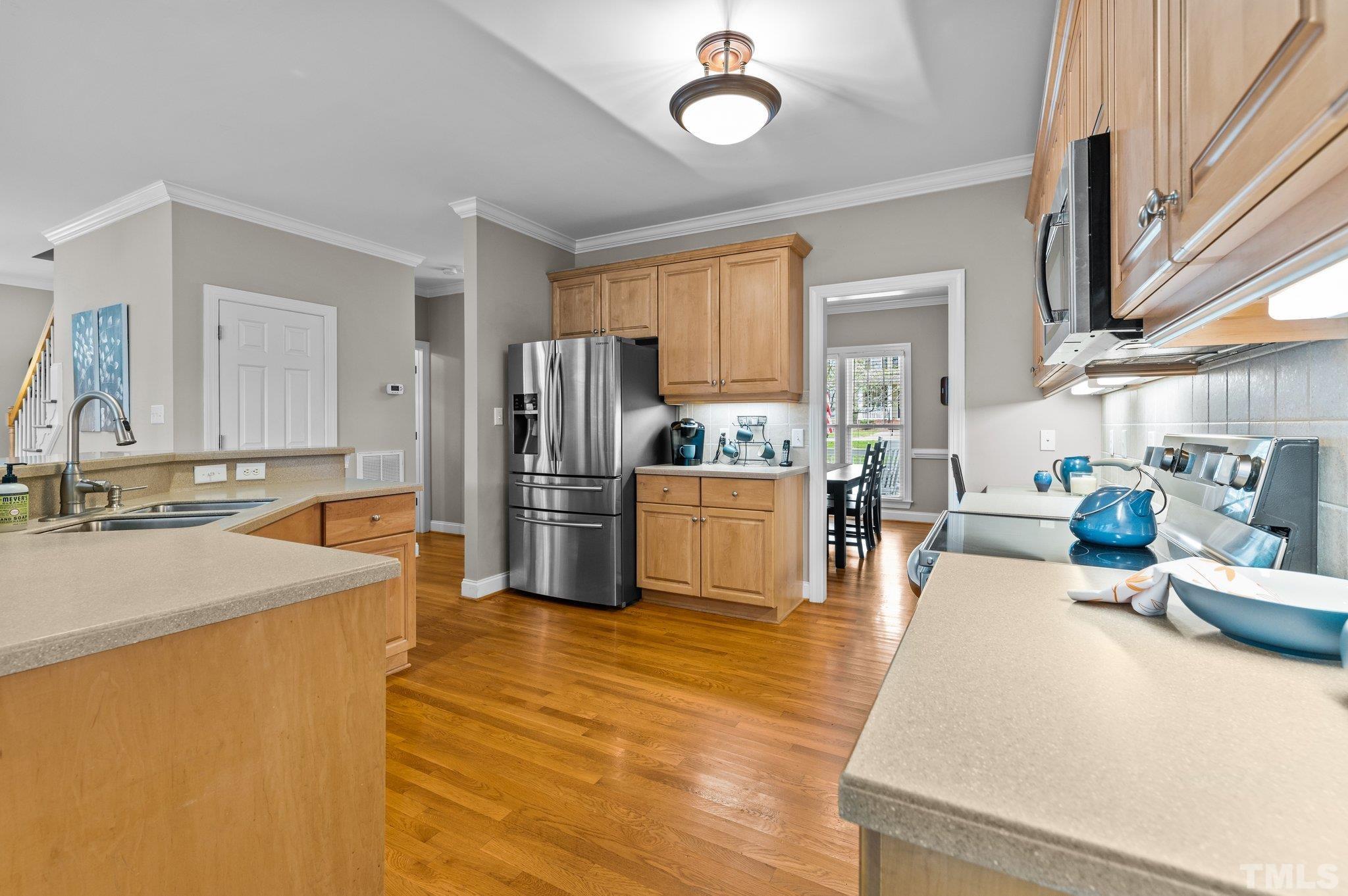 1209 Colonial Club Road Wake Forest, NC 27587 - Photo 9 of 28 a large kitchen with stainless steel appliances a refrigerator a stove a sink a dining table and chairs