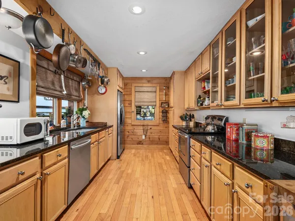 a large kitchen with stainless steel appliances granite countertop a lot of counter space and a wooden floor