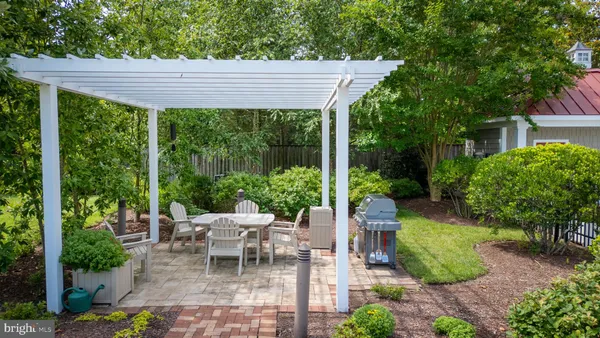 a view of a patio with table and chairs potted plants and large tree