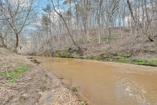 a view of a big house with a big yard and large trees