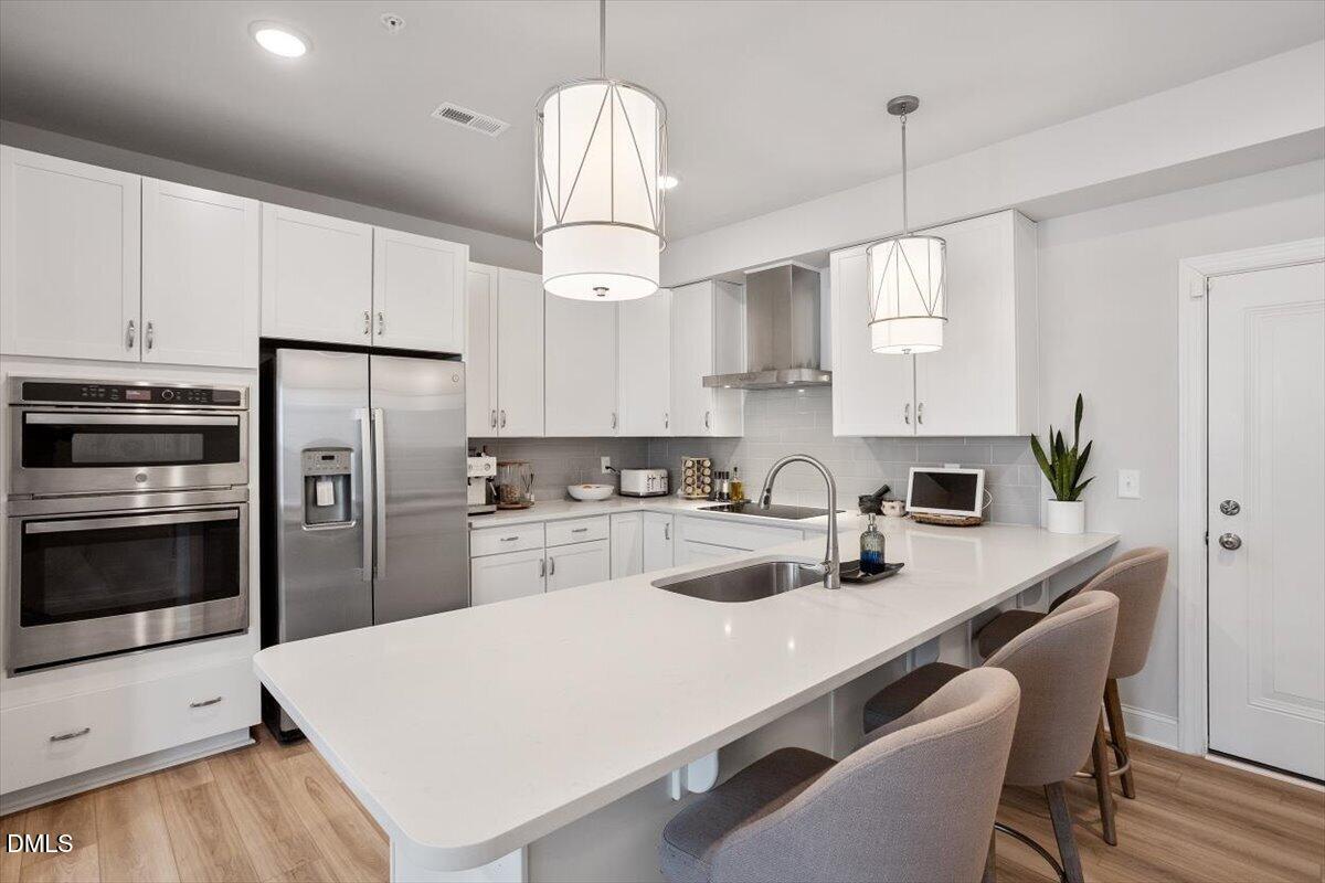 1234 Coach Sta Alley, Unit 101 Raleigh, NC 27601 - Photo 12 of 30 a kitchen with stainless steel appliances a stove a sink a refrigerator a center island and cabinets