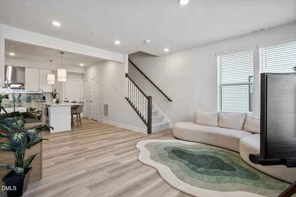 a living room with furniture and a dining table with wooden floor