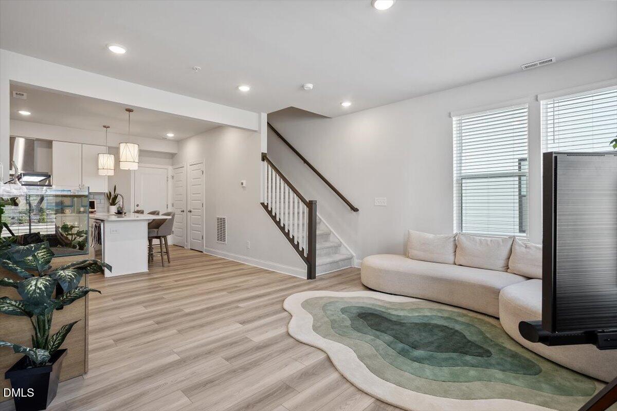 1234 Coach Sta Alley, Unit 101 Raleigh, NC 27601 - Photo 4 of 30 a living room with furniture and a dining table with wooden floor