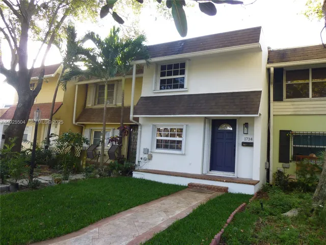 a view of a house with brick walls and a yard with a large tree