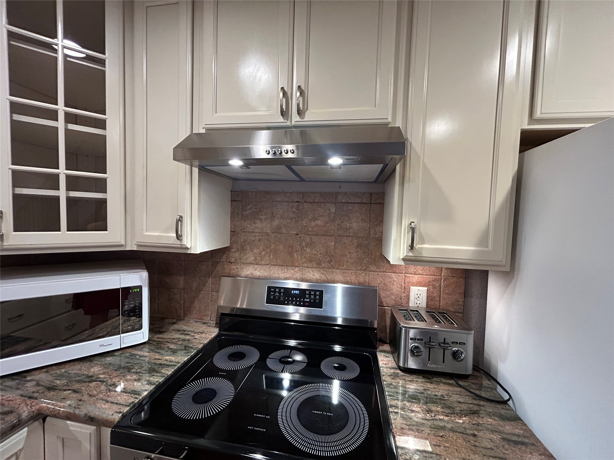 13034 Leader Street, Unit 965 Houston, TX 77072 - Photo 9 of 32 Aclose up of the 5-burner electric stove and the lighted vent hood above.