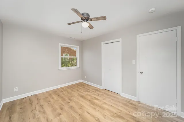 a view of a big room with windows and ceiling fan