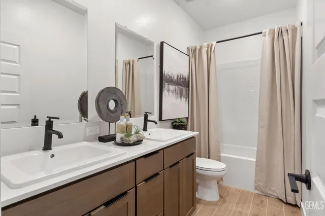 a bathroom with a double vanity sink toilet mirror and shower