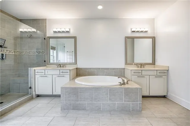 a bathroom with a tub a sink shower and mirror
