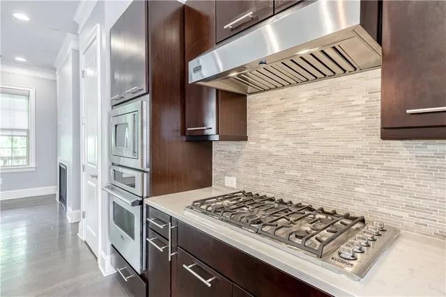 a kitchen with stainless steel appliances granite countertop a stove a refrigerator and wooden cabinets
