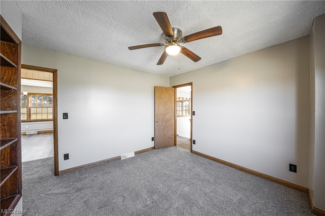 10258 Gilbert Road Newton Falls, OH 44444 - Photo 22 of 37 Empty room featuring dark carpet, ceiling fan, and a textured ceiling