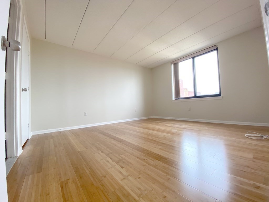 85 Brainerd Road, Unit 503 Boston, MA 02134 - Photo 9 of 21 an empty room with wooden floor and windows