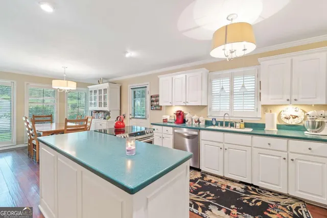 a kitchen with kitchen island granite countertop a stove a sink a dining table and chairs with wooden floor