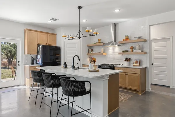a kitchen with stainless steel appliances granite countertop a sink a stove a refrigerator and island with wooden floor