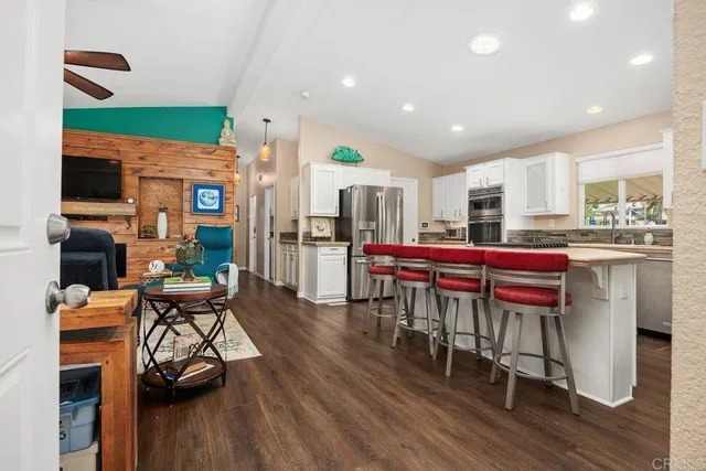 a kitchen with stainless steel appliances kitchen island granite countertop a table chairs and a refrigerator