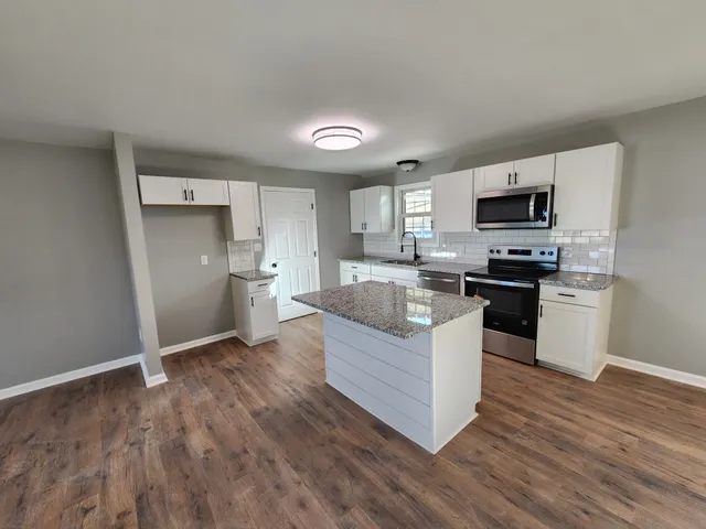 a kitchen with stainless steel appliances granite countertop a stove top oven a sink and a granite counter tops