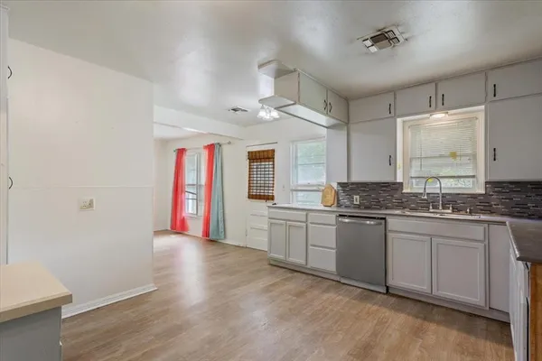 a kitchen with stainless steel appliances granite countertop a sink cabinets and wooden floor
