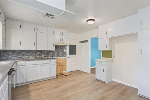 a kitchen with granite countertop a sink a stove a refrigerator and white cabinets