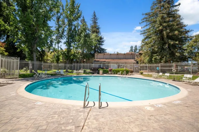 a view of a swimming pool with a lounge chair and trees in the background
