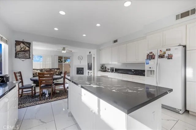 a large kitchen with stainless steel appliances lots of white furniture a refrigerator and a stove