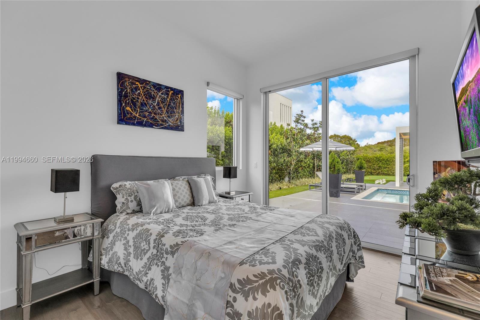 16631 Sunset Way Weston, FL 33326 - Photo 17 of 59 a bedroom with a large bed and a flat tv screen next to a window