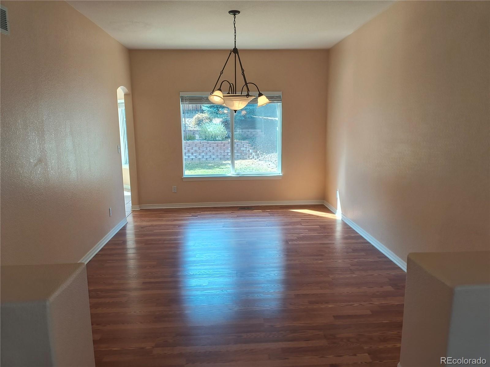 10145 Charissglen Lane Highlands Ranch, CO 80126 - Photo 11 of 39 a view of a room with wooden floor a chandelier and windows