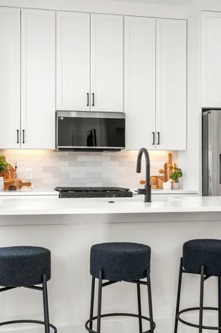 a kitchen with stainless steel appliances a stove a sink and white cabinets