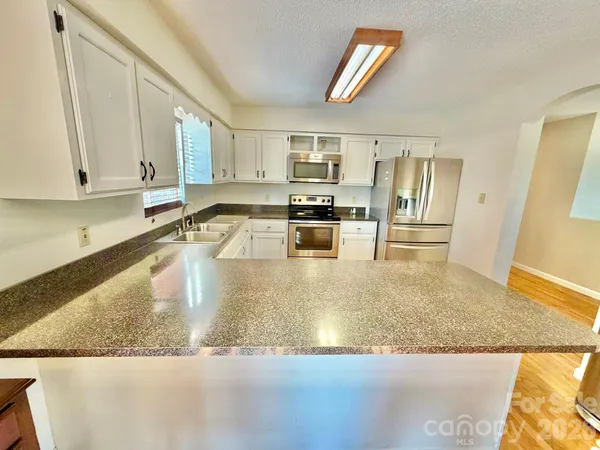 a kitchen with stainless steel appliances granite countertop a sink a stove top oven a counter space and cabinets