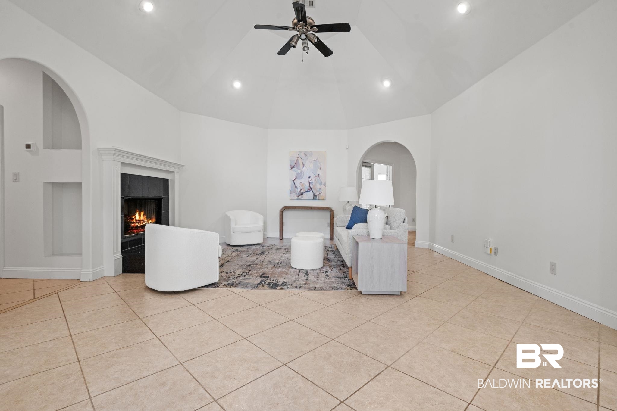29634 St George Street Daphne, AL 36526 - Photo 13 of 47 Sitting room featuring arched walkways, ceiling fan, built in shelves, light tile patterned flooring, and a lit fireplace
