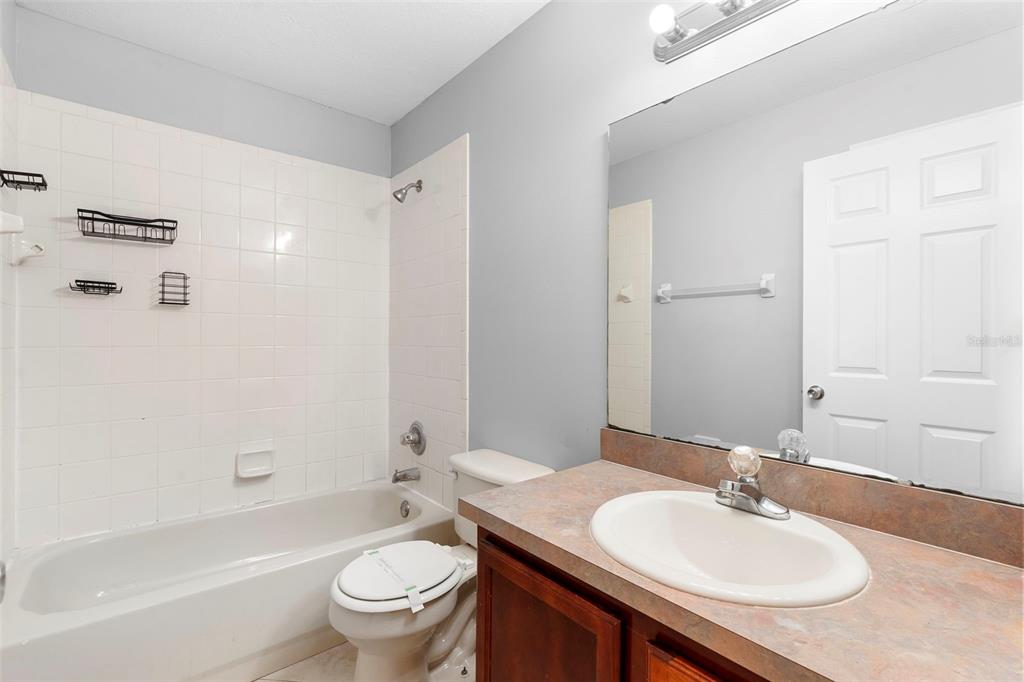 559 Saddle Ridge Drive Davenport, FL 33896 - Photo 24 of 42 a bathroom with a granite countertop sink toilet a mirror and shower