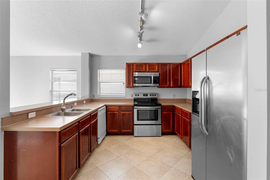 559 Saddle Ridge Drive Davenport, FL 33896 - Photo 36 of 42 a kitchen with stainless steel appliances granite countertop a sink stove refrigerator and cabinets